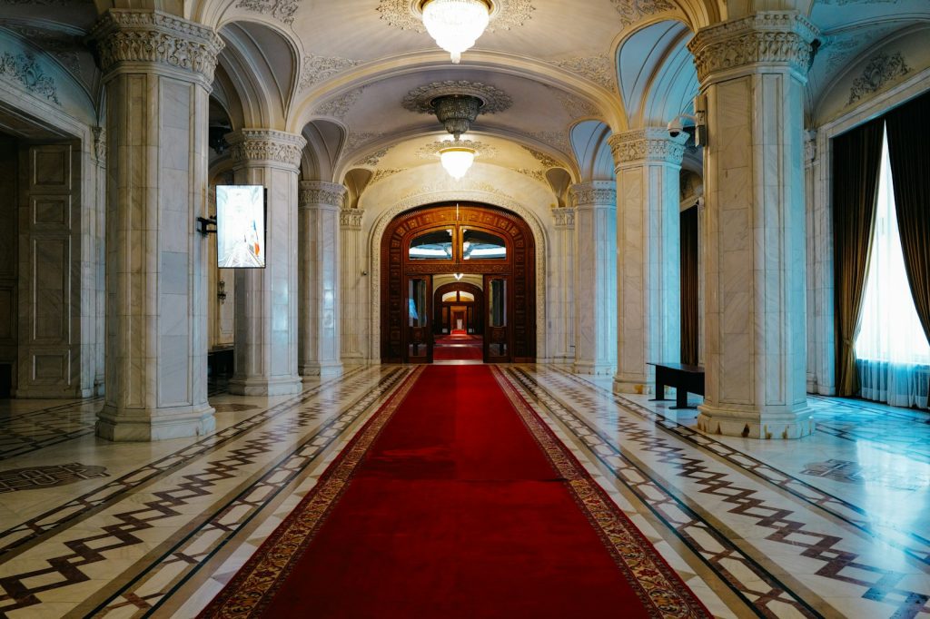 A long red carpet leading through a grand marble hallway with ornate columns