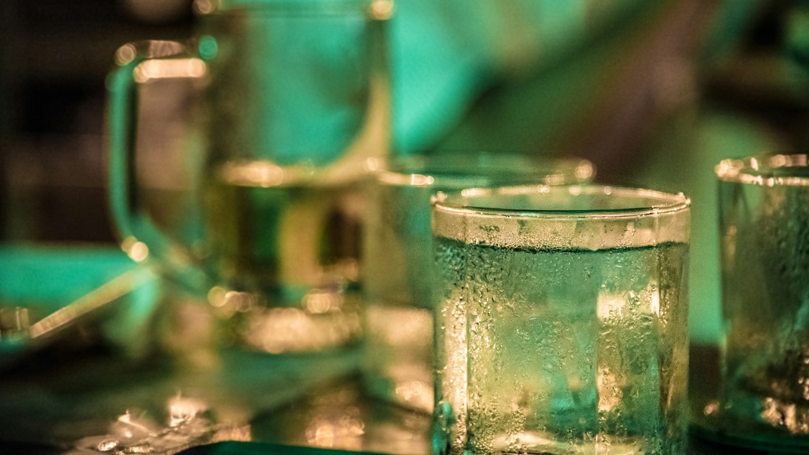Glasses of water and beer side by side on a dark dining table
