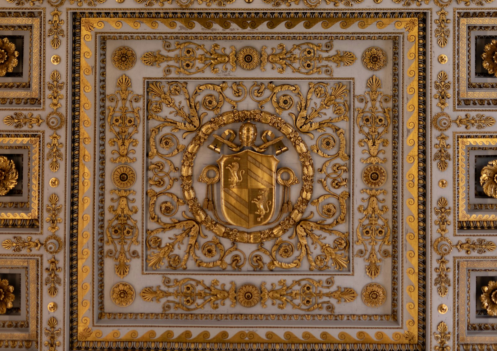 Ornate white and gold baroque ceiling with a golden crest, a symbol of opulent couture glamour