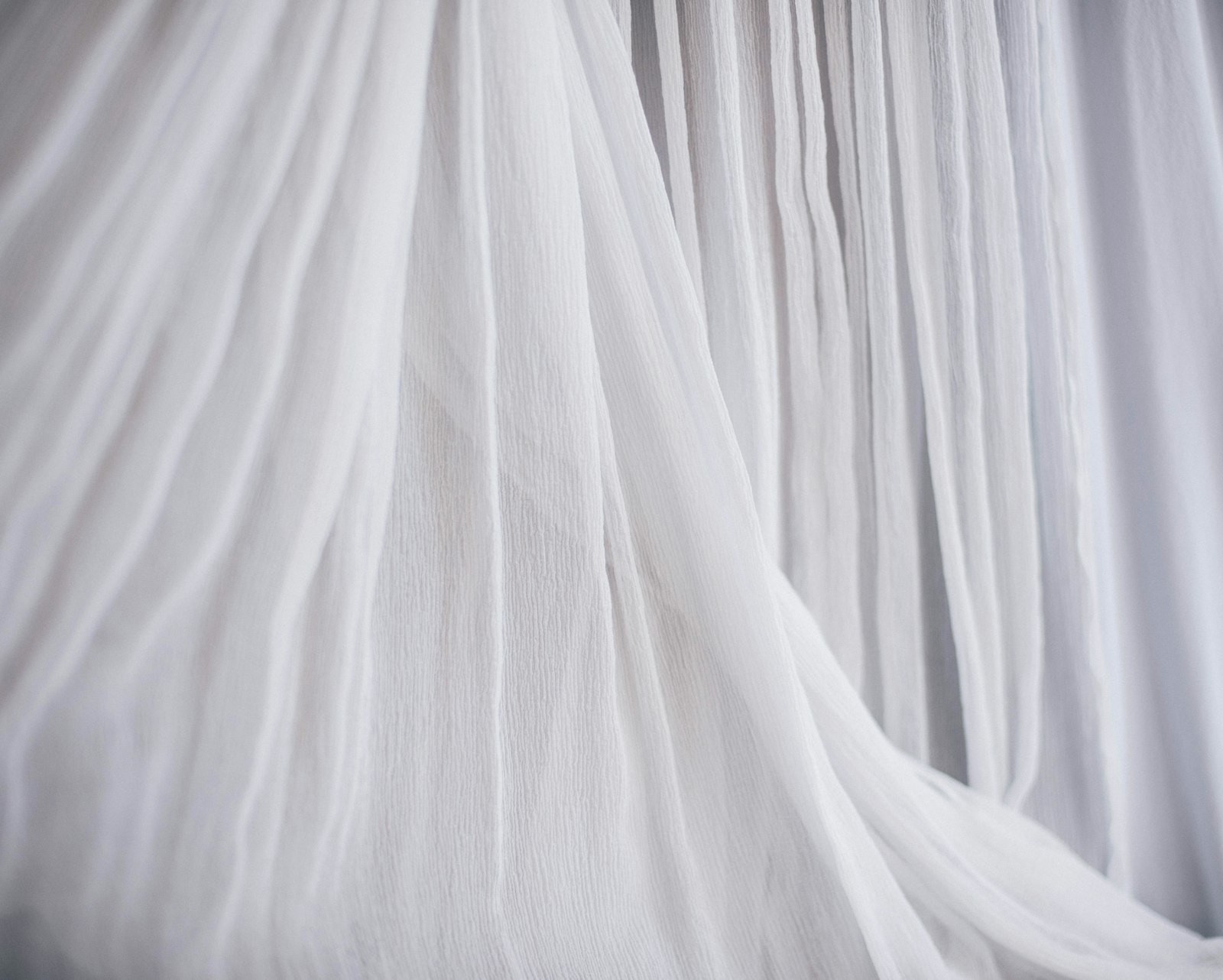 White, airy fabric flowing in soft folds, symbolising lightness and couture craftsmanship