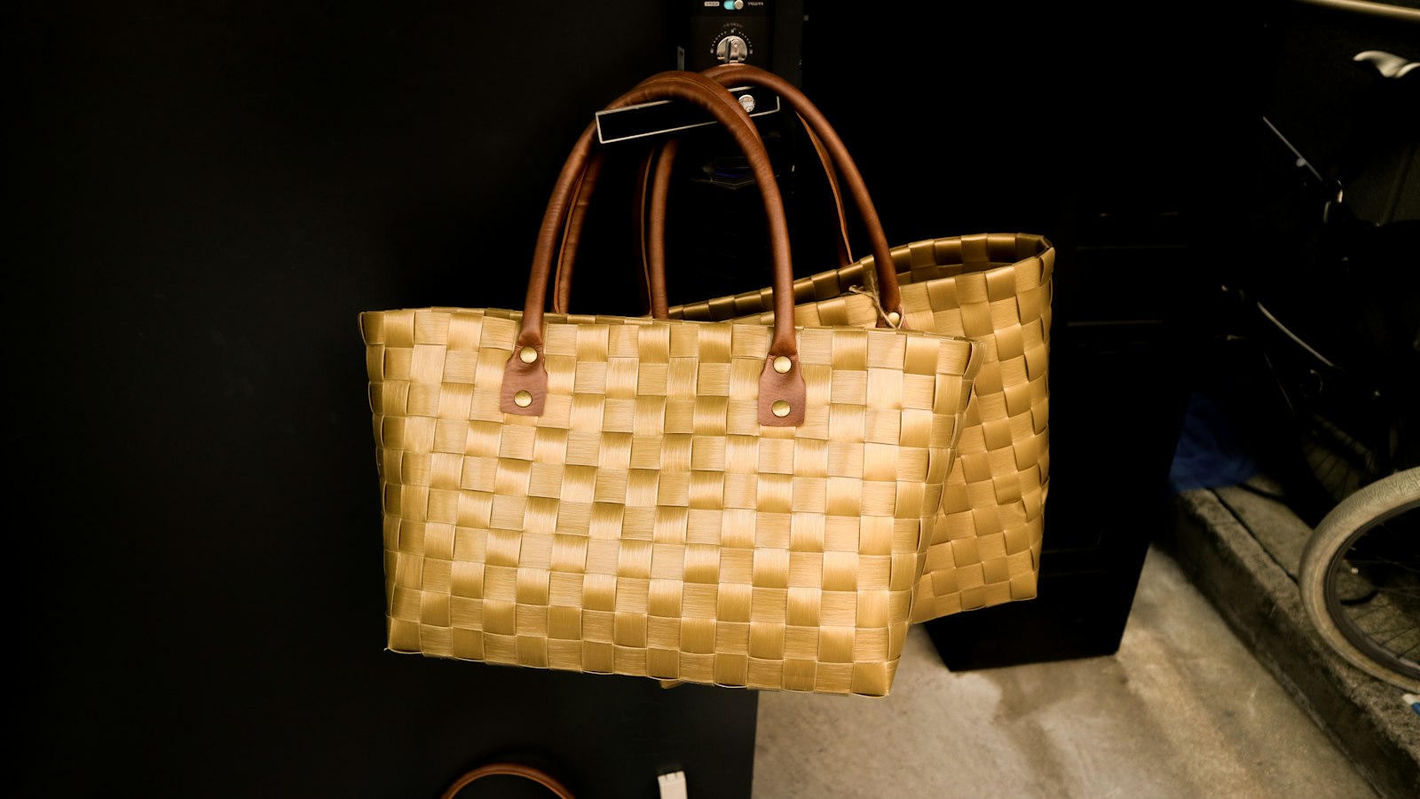Two brown woven leather tote bags photographed side by side against a light background
