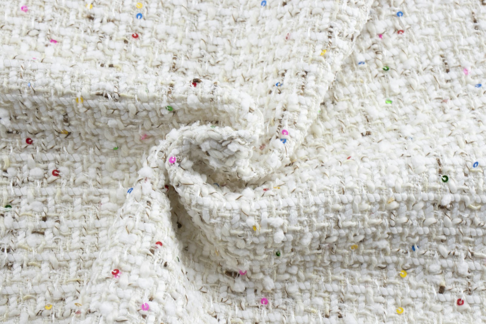 Close-up of a pale bouclé tweed fabric woven with colorful sequins