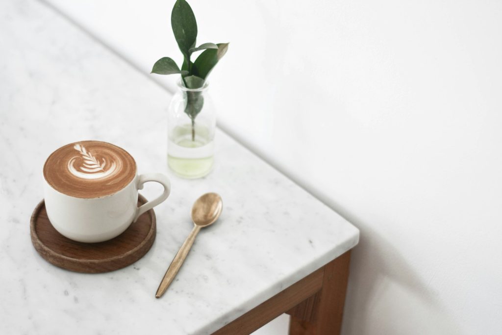 A cappuccino with milk foam in a white cup on a light marble table