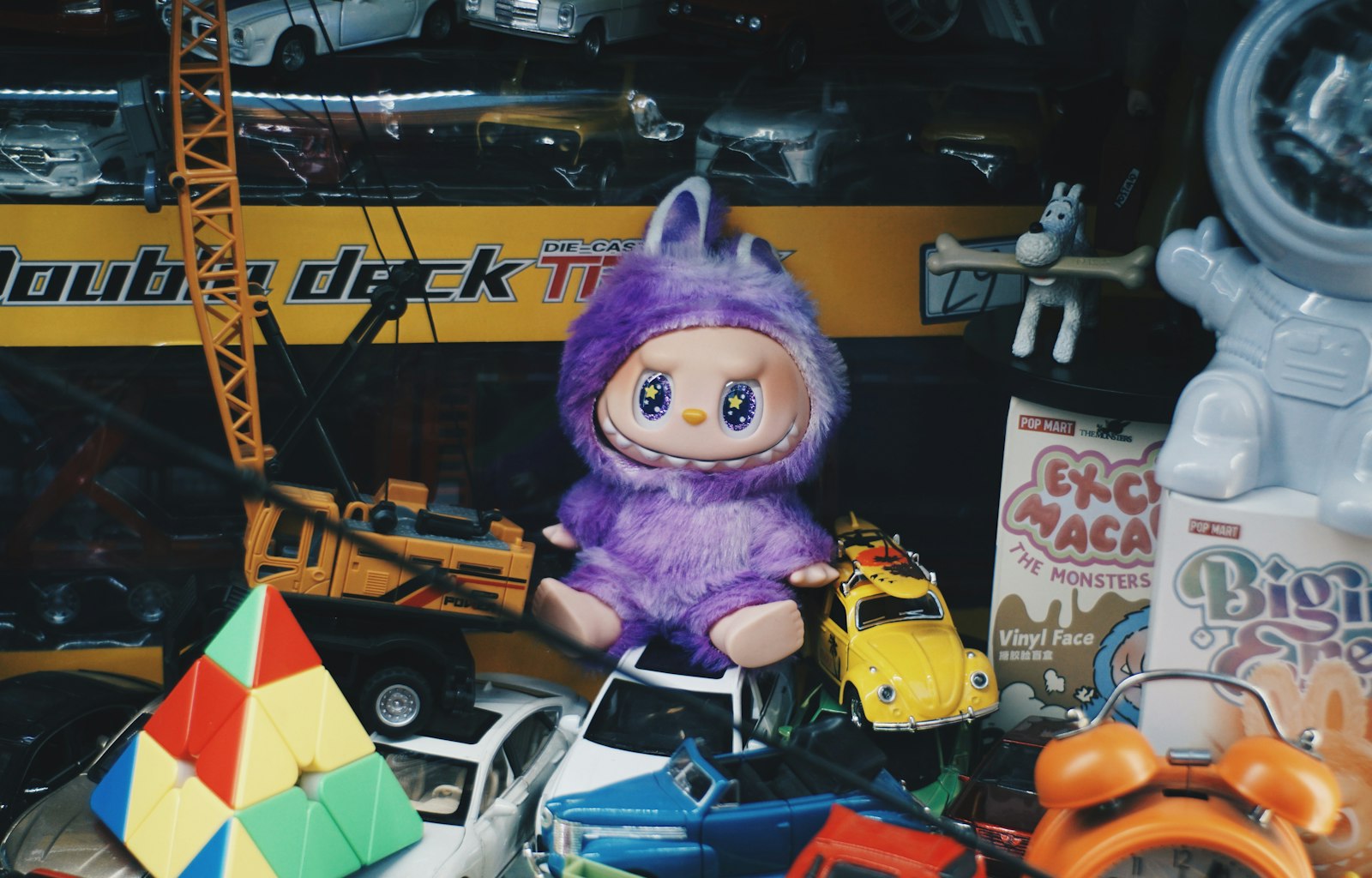 A purple fuzzy collectible toy sitting among other small vinyl toys and figurines