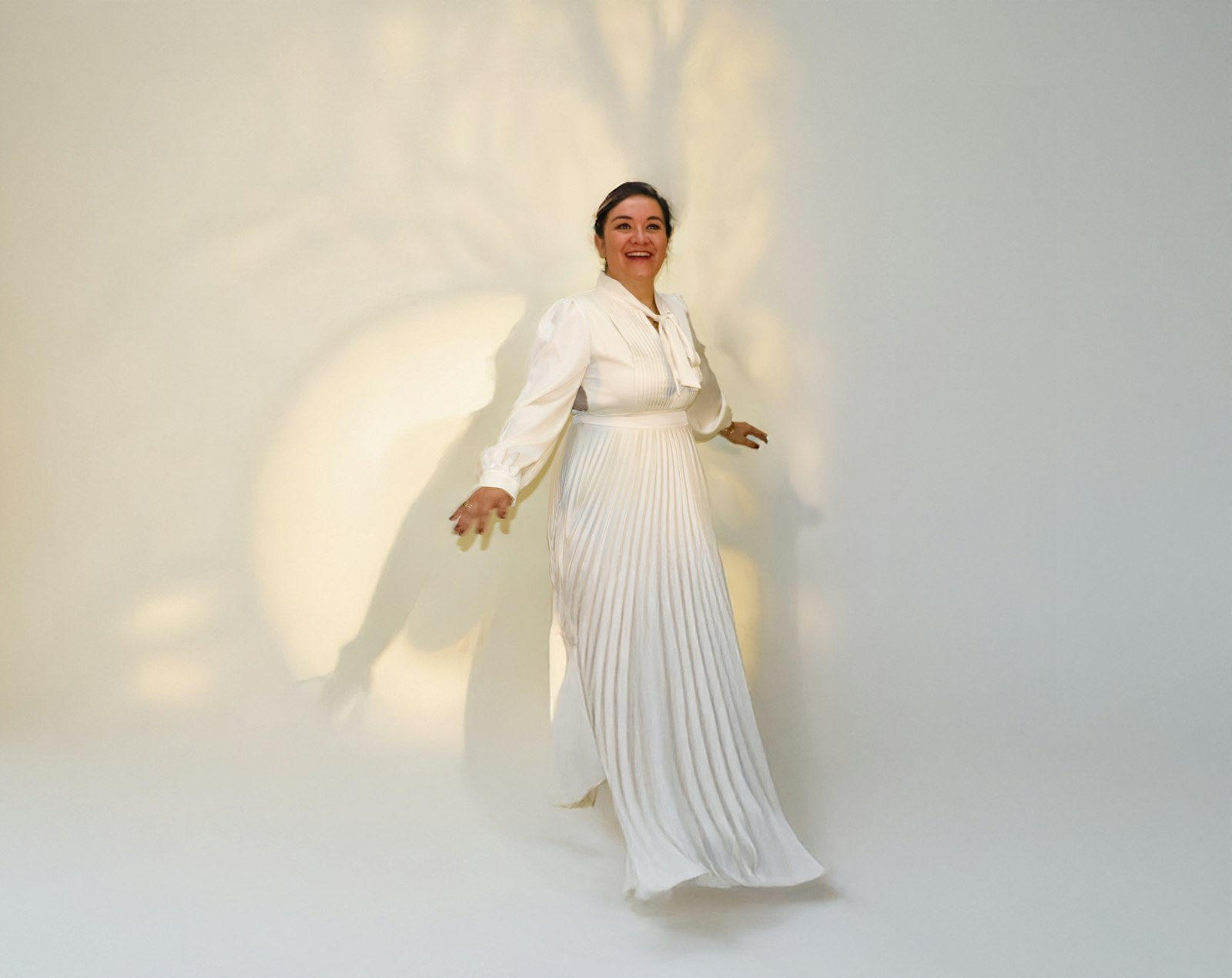 Frau in einem eleganten weißen Kleid mit plissiertem Rock – Symbolbild für leichte, fließende Mode