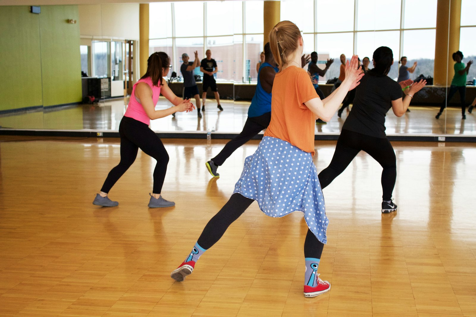 Women in activewear dancing in a bright dance studio in front of a mirror
