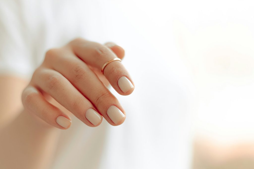 Close-up of a hand with a clean white manicure on a light background