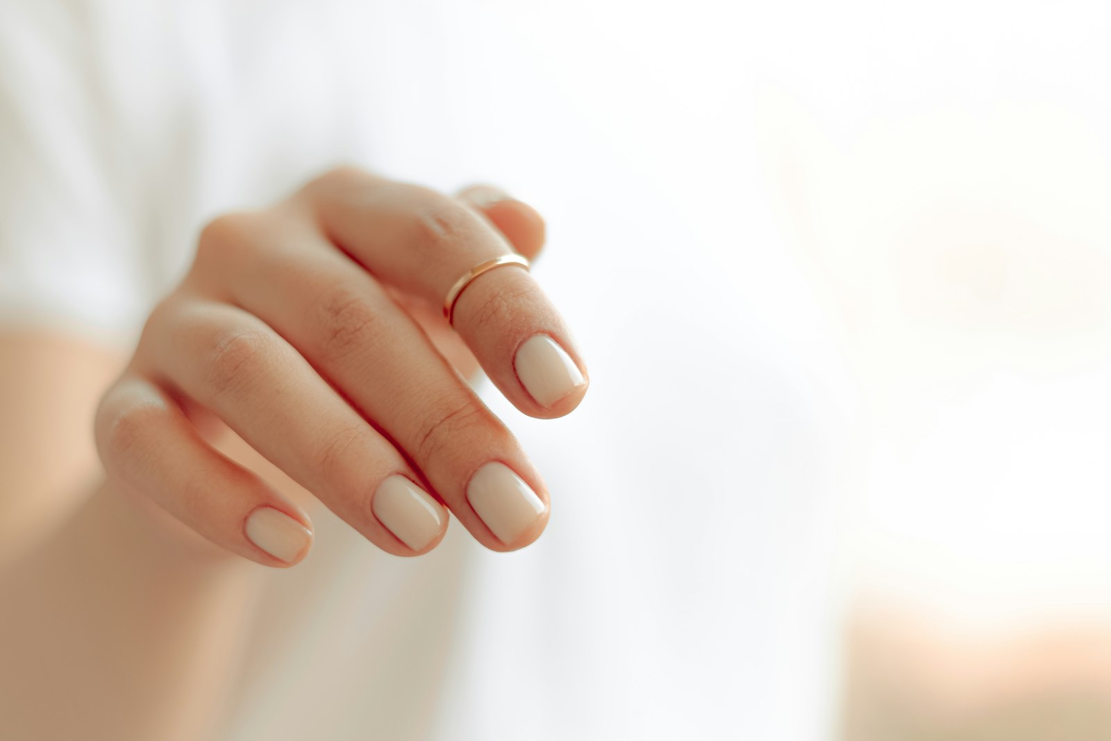 Close-up of a hand with a clean white manicure on a light background