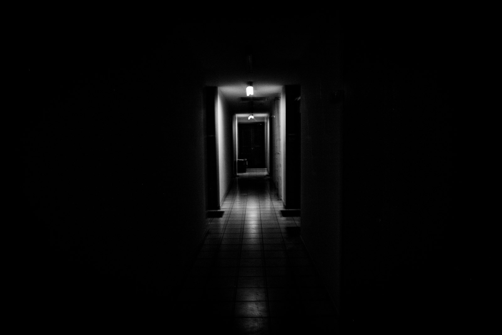 A dark hallway with a single light glowing at the far end, evoking the mood of a horror film