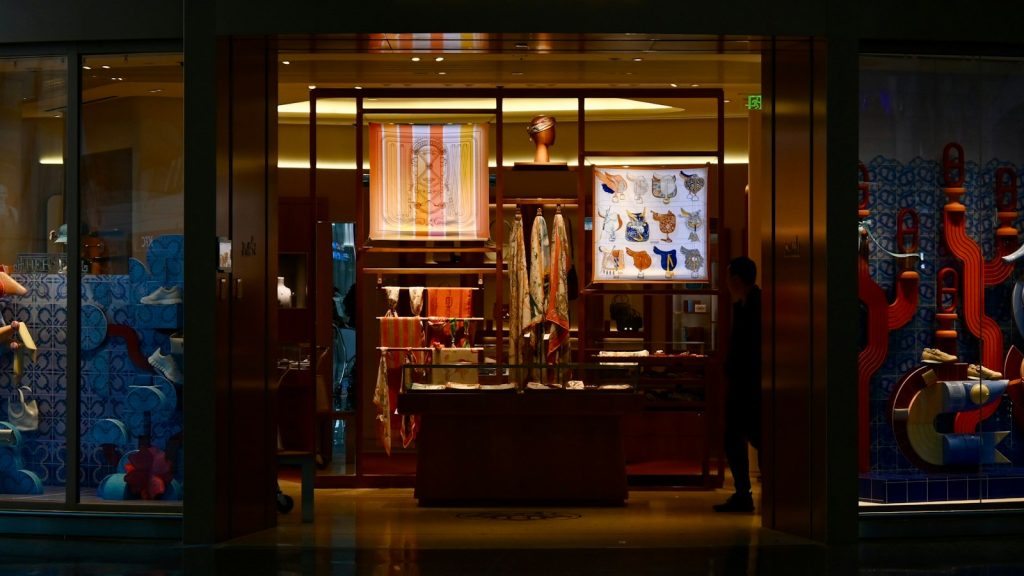 Illuminated luxury boutique window display at night on a city street
