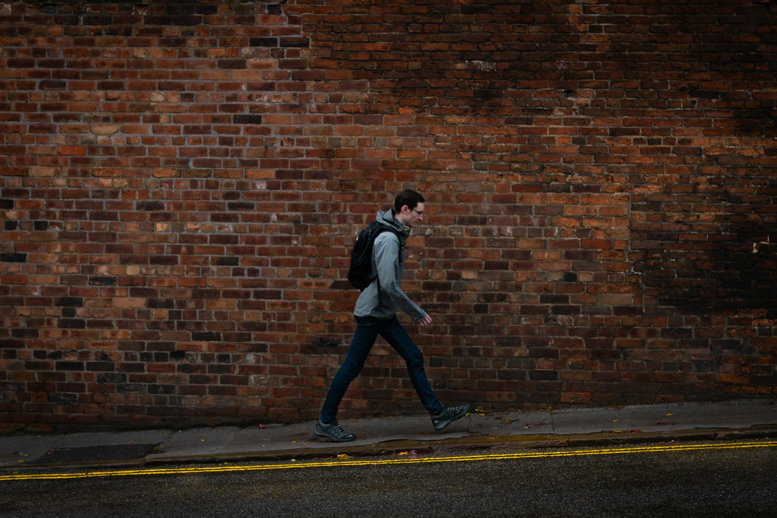 Man walking alone up a steep city sidewalk in muted evening light