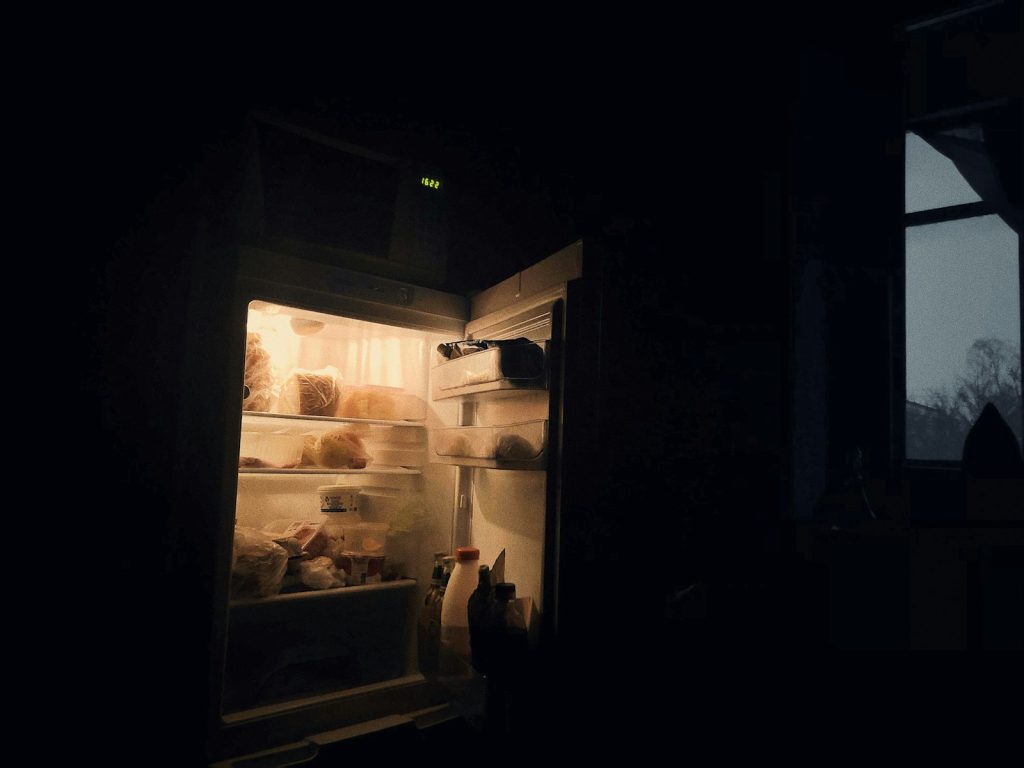 An open refrigerator glowing in a dark room at night