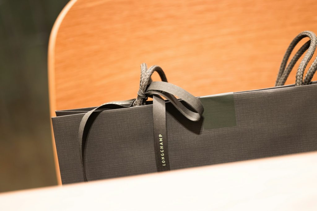 Black luxury shopping bag tied with a ribbon against a light background
