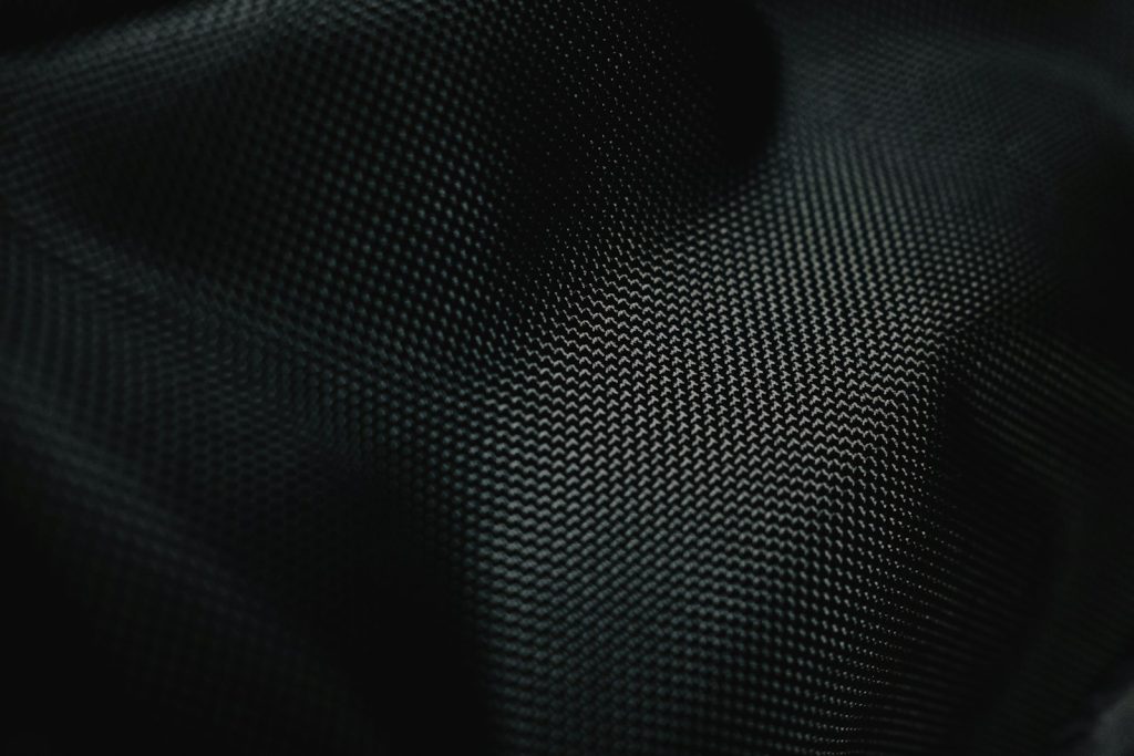 Close-up of a dark woven technical fabric with fine texture, symbolising performance textiles