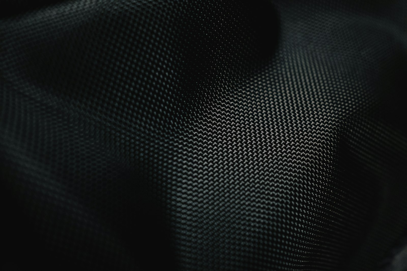 Close-up of a dark woven technical fabric with fine texture, symbolising performance textiles