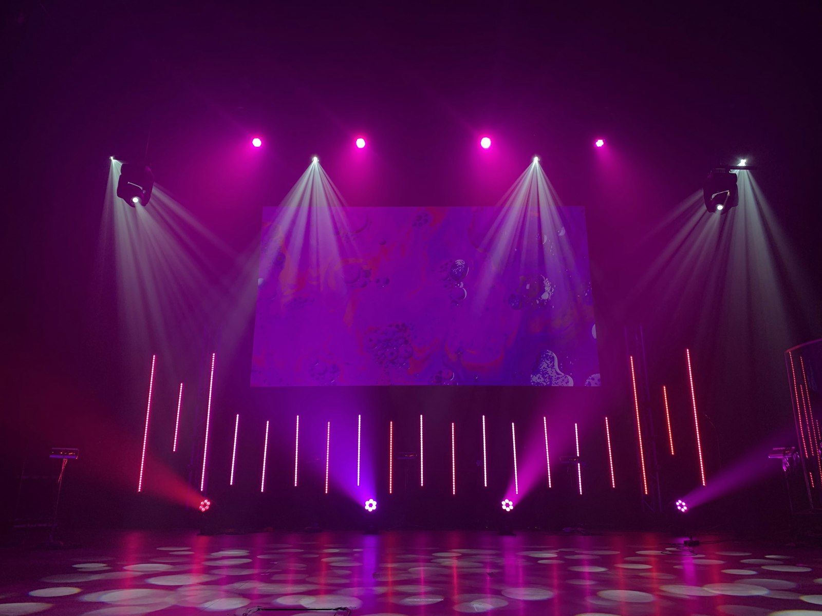 Empty concert stage bathed in purple and pink spotlights before a show
