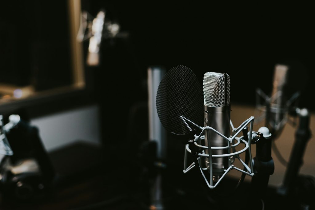 Silver and black condenser microphone in a dark recording studio