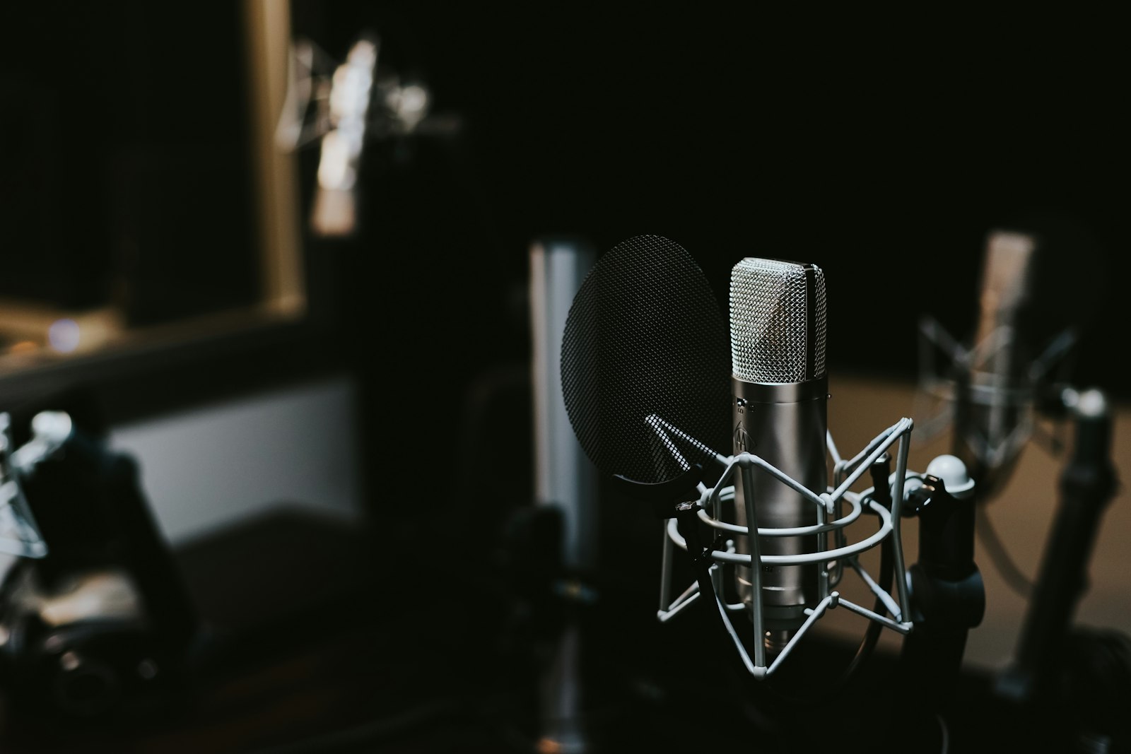 Silver and black condenser microphone in a dark recording studio