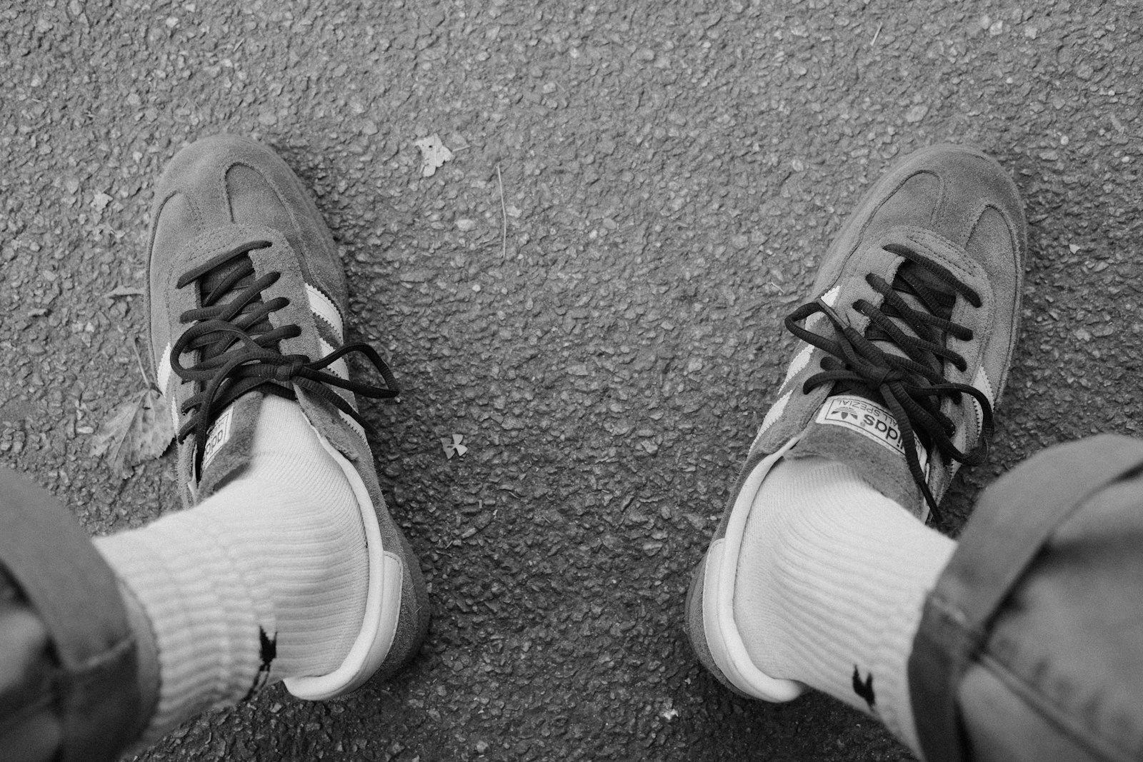 A pair of suede retro sneakers with white socks standing on textured asphalt