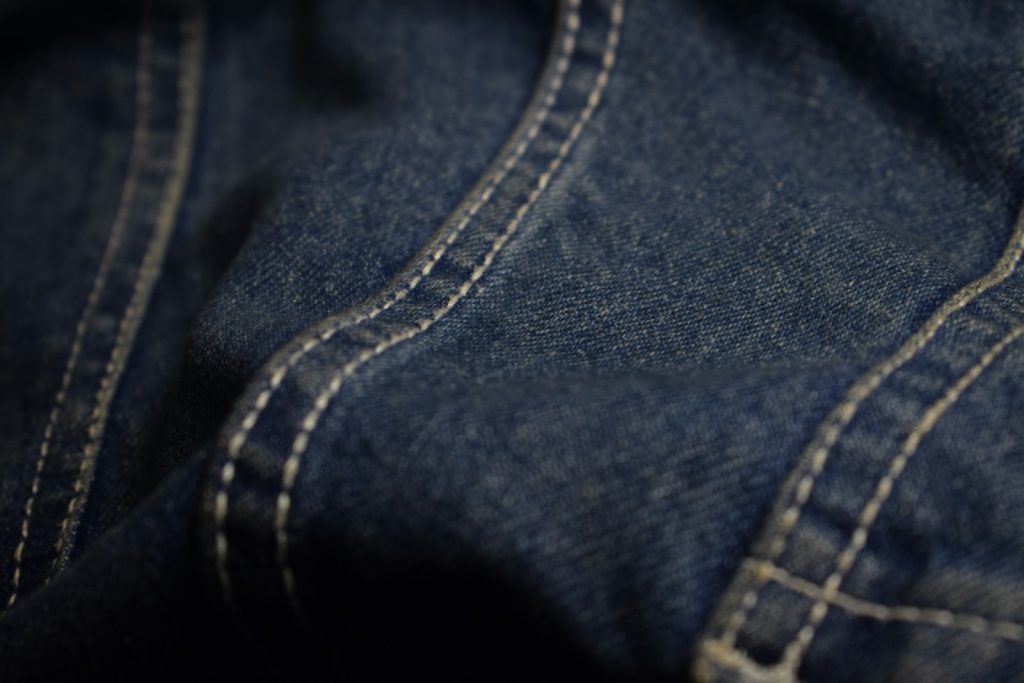 Close-up of dark blue denim fabric with thick white contrast stitching