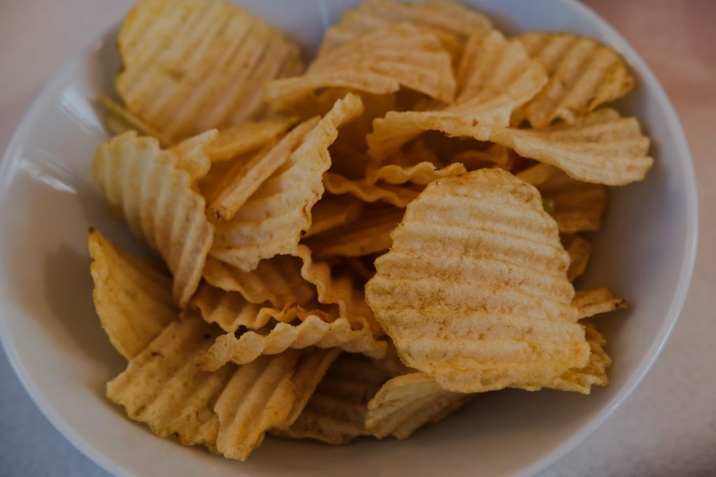 Wavy potato chips filling a white bowl, a typical ultra-processed snack