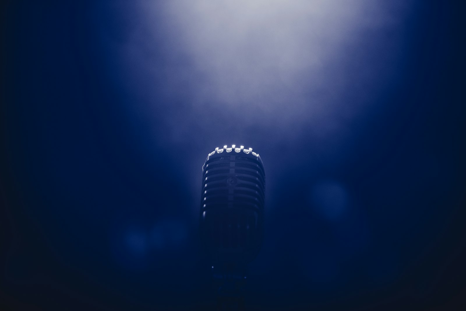 Vintage microphone on a stand under blue stage light
