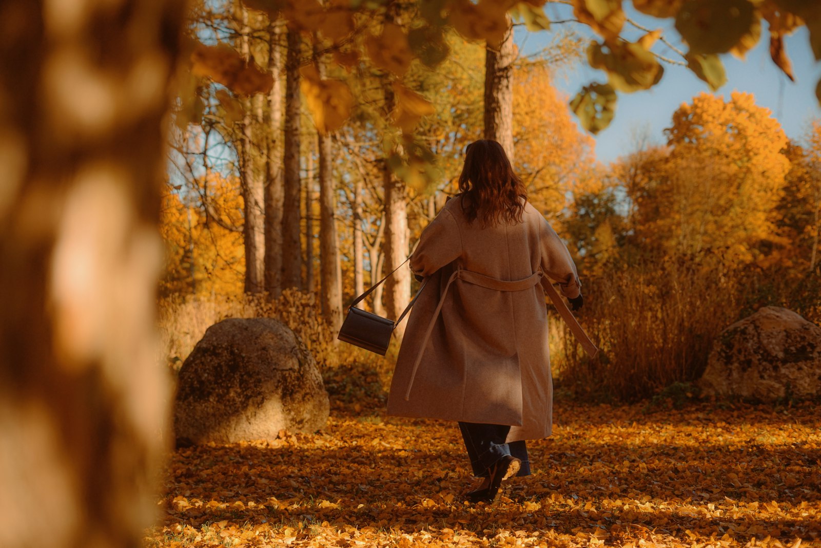 A woman walking along a path through an autumn forest with colorful leaves